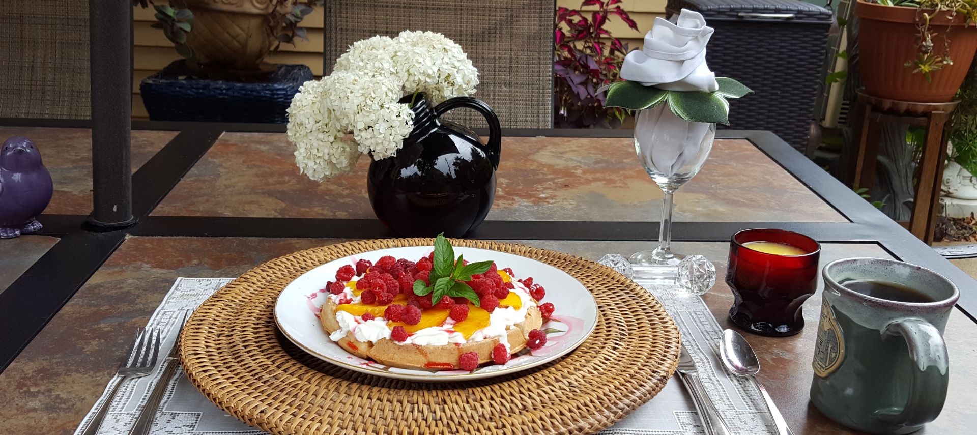 Homemade waffles served with whip cream, local peaches, and berries fresh from our garden at The Queen, A Victorian Bed and Breakfast in Bellefonte, PA. Served on the patio with view of pollinator gardens!