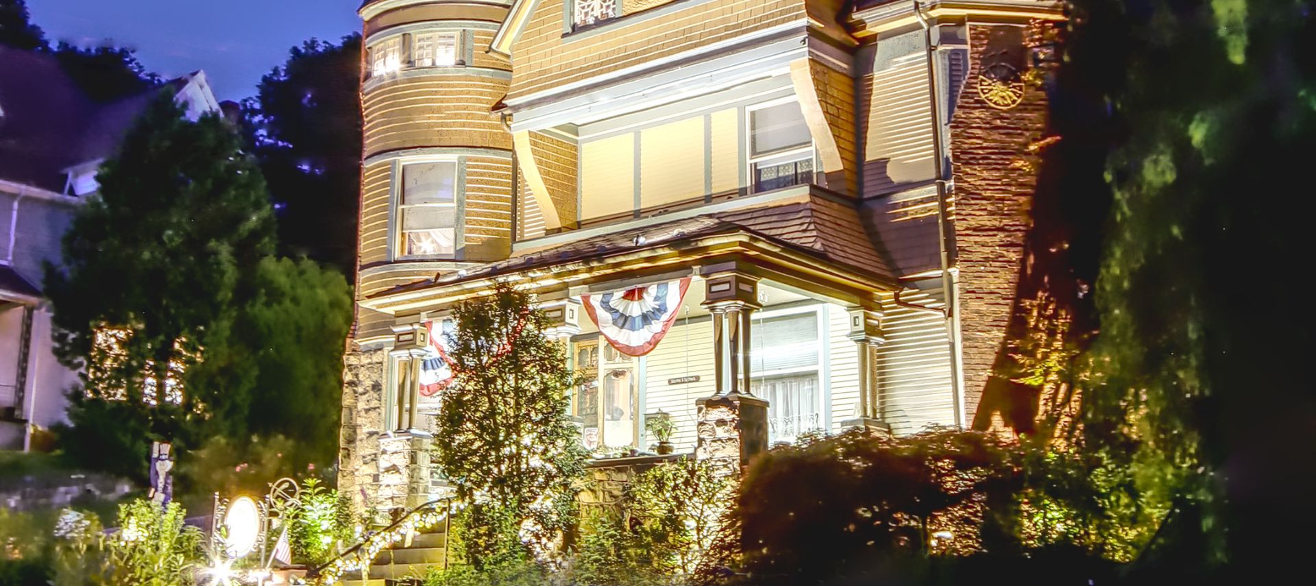 Image of The Queen, A Victorian Bed and Breakfast in Bellefonte, PA. Lit up at night, beautiful lighting. Historic building.